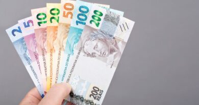 Pessoa segurando cédulas de real brasileiro de diferentes valores, representando organização financeira, economia e planejamento para guardar dinheiro com data para retirar.